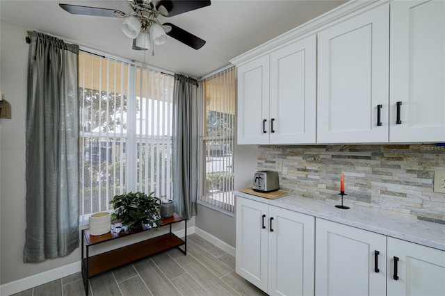 interior space featuring light stone countertops, white cabinetry, backsplash, and ceiling fan