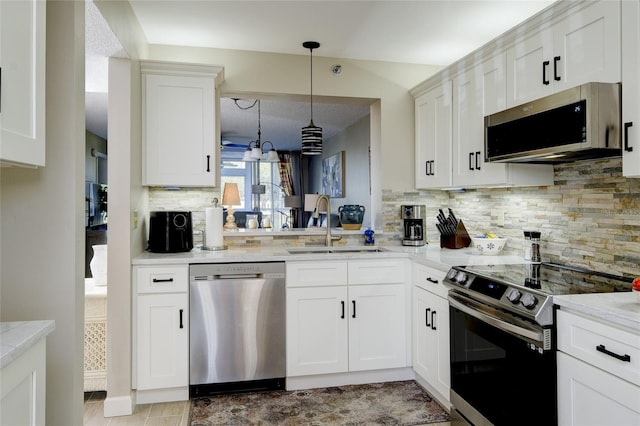 4550 Pinebrook Cir Unit 103, Bradenton, FL 34209 - kitchen featuring appliances with stainless steel finishes, a sink, white cabinetry, backsplash, and pendant lighting