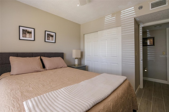 bedroom featuring a closet, ceiling fan, a textured ceiling, and dark hardwood / wood-style flooring