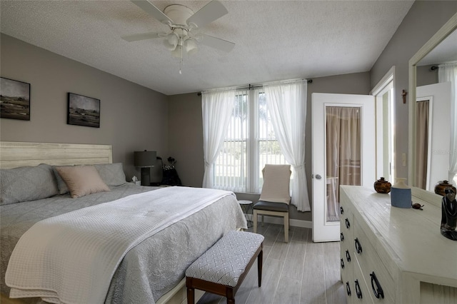 bedroom featuring light hardwood / wood-style floors, a textured ceiling, and ceiling fan