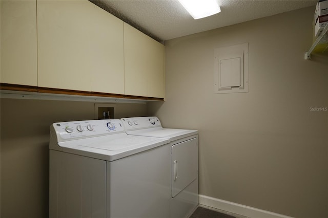 washroom with washer and dryer, electric panel, a textured ceiling, and cabinets