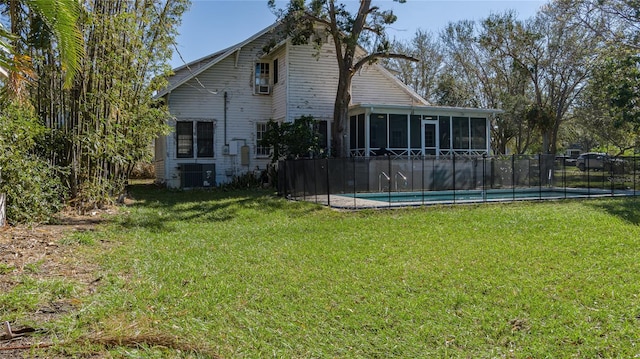 rear view of property featuring a sunroom, a lawn, cooling unit, and a fenced in pool