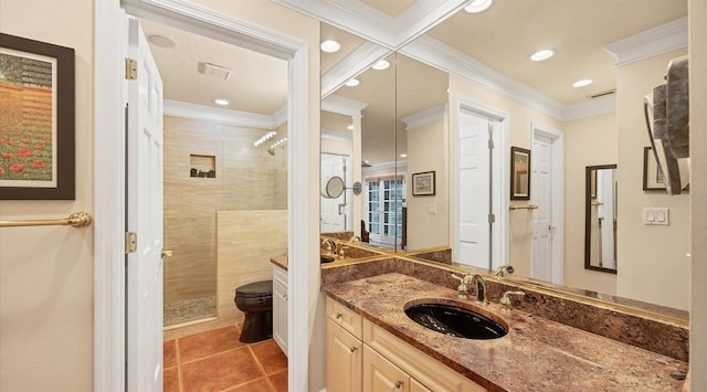 bathroom featuring a tile shower, toilet, ornamental molding, vanity, and tile patterned flooring