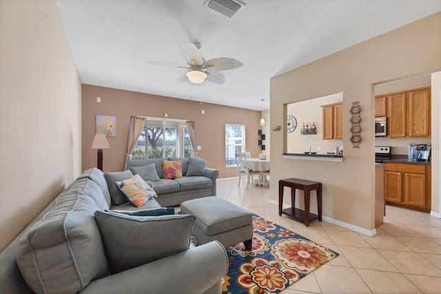 living room with a textured ceiling, light tile patterned floors, and ceiling fan