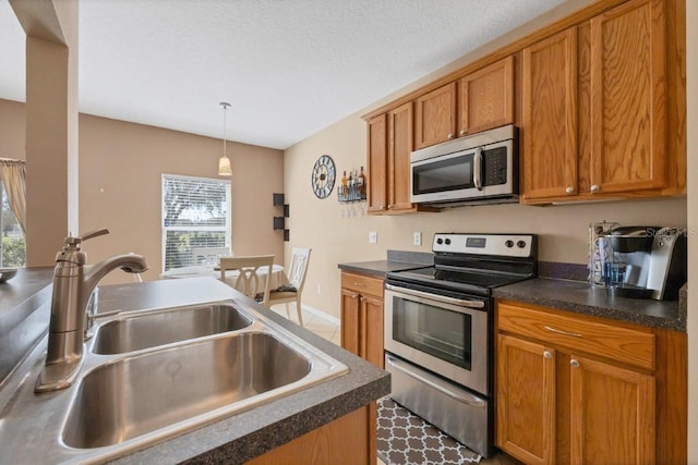 kitchen with sink, appliances with stainless steel finishes, pendant lighting, and a healthy amount of sunlight