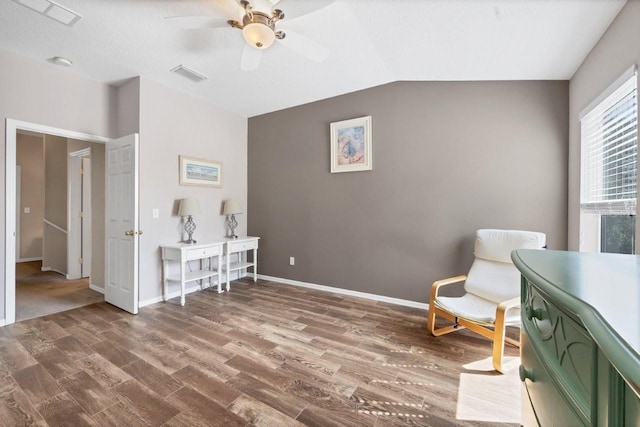 living area with hardwood / wood-style flooring, ceiling fan, and vaulted ceiling