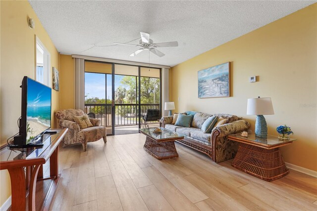 living room with a wall of windows, ceiling fan, a textured ceiling, and light wood-type flooring