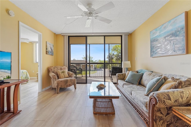 living room featuring a textured ceiling, expansive windows, light hardwood / wood-style flooring, and ceiling fan