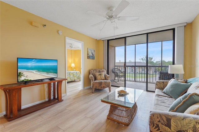 living room with ceiling fan, light hardwood / wood-style flooring, expansive windows, and a textured ceiling