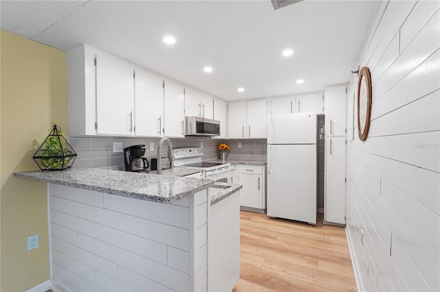 kitchen featuring white cabinets, light wood-type flooring, white appliances, and kitchen peninsula