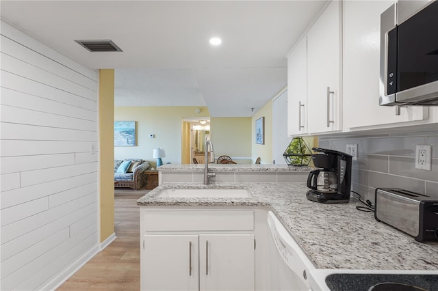 kitchen with light stone countertops, white cabinetry, sink, kitchen peninsula, and light hardwood / wood-style floors