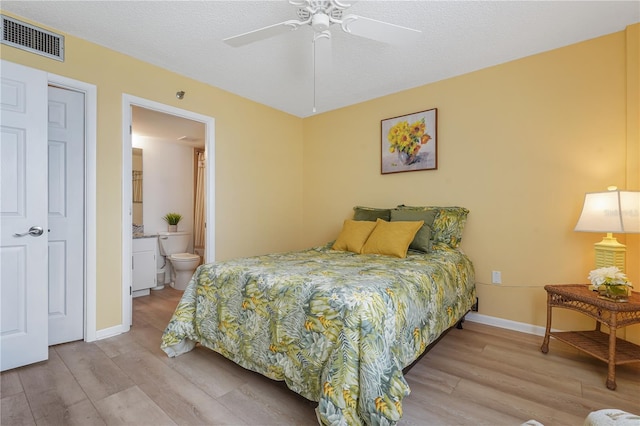 bedroom featuring ensuite bath, ceiling fan, light hardwood / wood-style flooring, and a textured ceiling