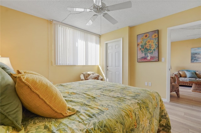 bedroom with ceiling fan, light wood-type flooring, and a textured ceiling