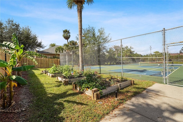 view of tennis court featuring a gate, a garden, and fence