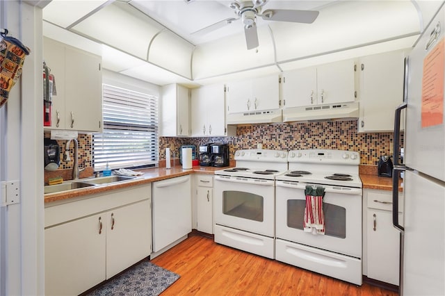 kitchen with white appliances, under cabinet range hood, white cabinets, and a sink