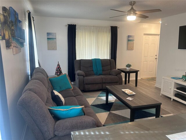 living room featuring baseboards, wood finished floors, and ceiling fan