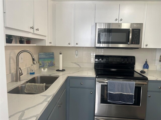 kitchen with gray cabinetry, a sink, white cabinets, appliances with stainless steel finishes, and tasteful backsplash