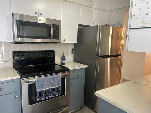 kitchen with decorative backsplash, light stone counters, appliances with stainless steel finishes, and gray cabinetry