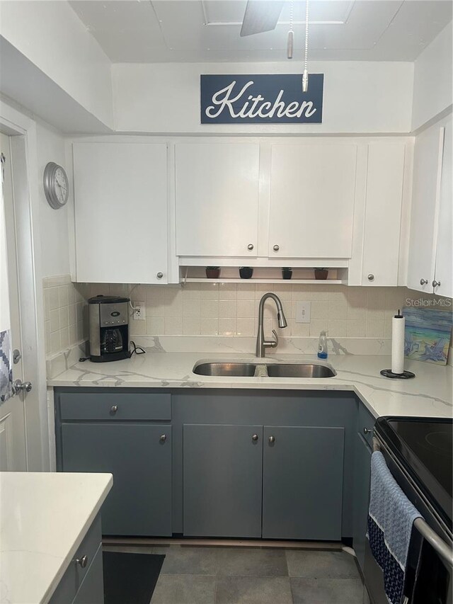 kitchen with a sink, tasteful backsplash, gray cabinetry, and white cabinetry