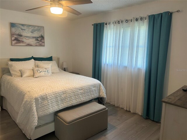 bedroom featuring ceiling fan, a textured ceiling, and wood finished floors