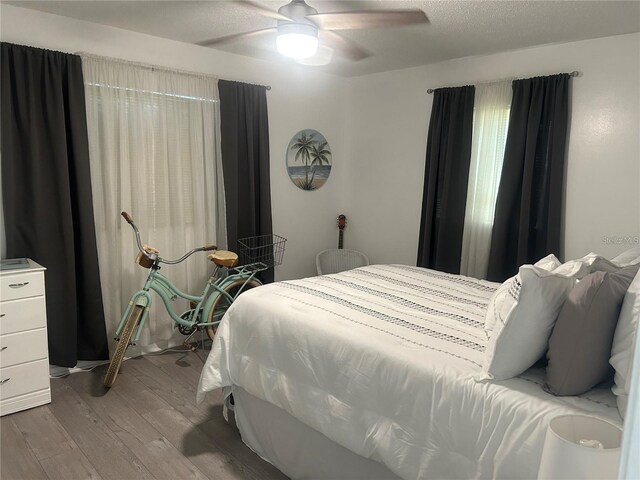 bedroom with a textured ceiling, ceiling fan, and wood finished floors