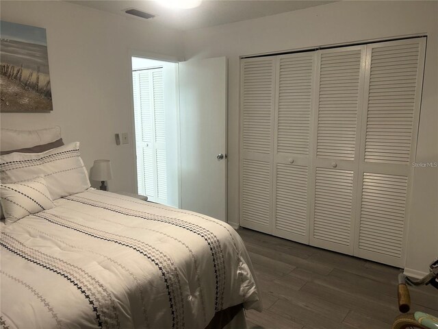 bedroom featuring dark wood finished floors, visible vents, and a closet