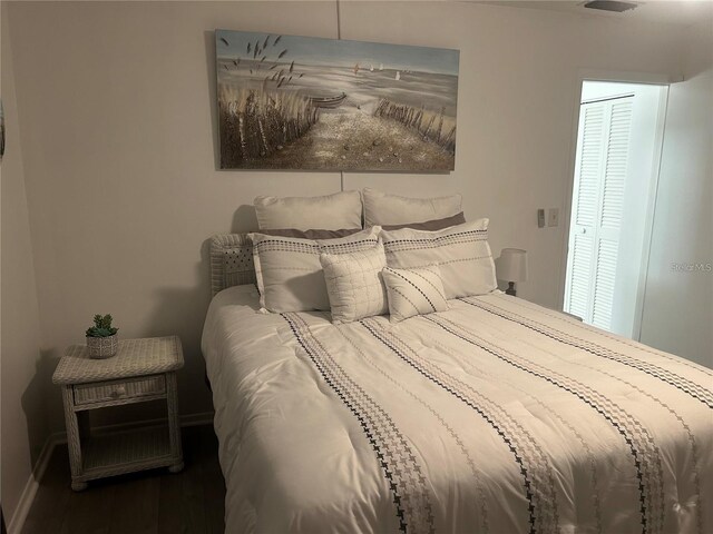 bedroom with wood finished floors, visible vents, and baseboards