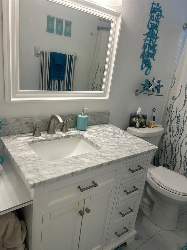 bathroom with marble finish floor, toilet, and vanity