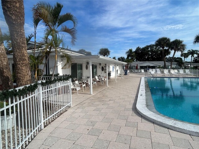 community pool with a patio area and fence