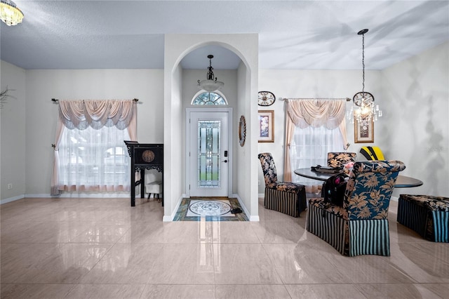 entryway with a chandelier, a textured ceiling, and plenty of natural light