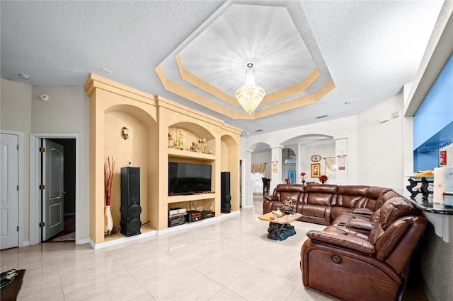 tiled living room featuring a textured ceiling, built in shelves, and a raised ceiling