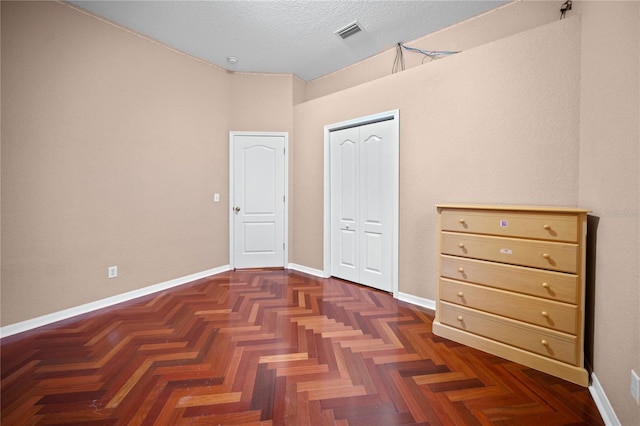 unfurnished bedroom featuring dark parquet floors and a textured ceiling