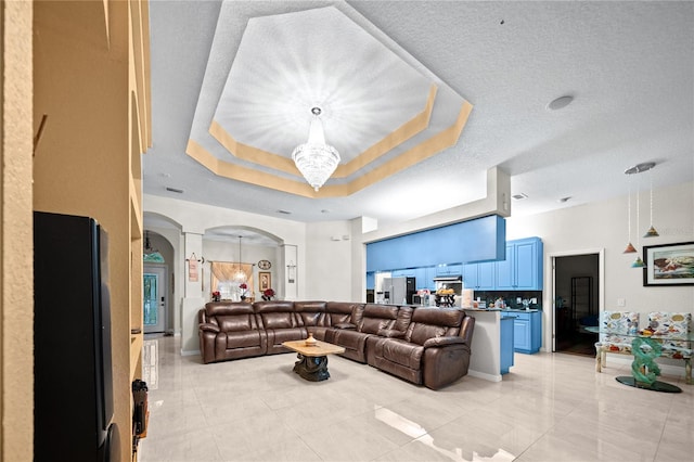 living room with a textured ceiling, a chandelier, and a raised ceiling