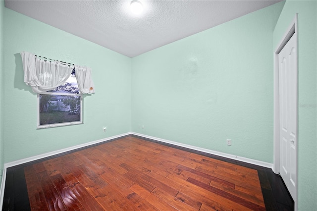 empty room featuring hardwood / wood-style flooring and a textured ceiling