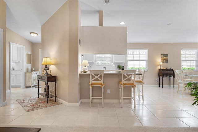 kitchen with a kitchen breakfast bar, plenty of natural light, kitchen peninsula, and light tile patterned floors