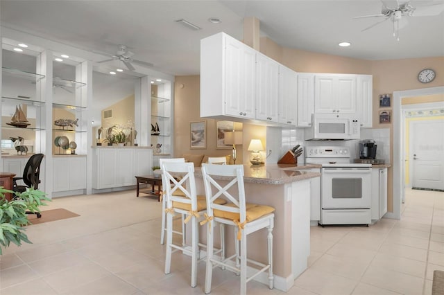 kitchen featuring white cabinetry, white appliances, a breakfast bar, and kitchen peninsula