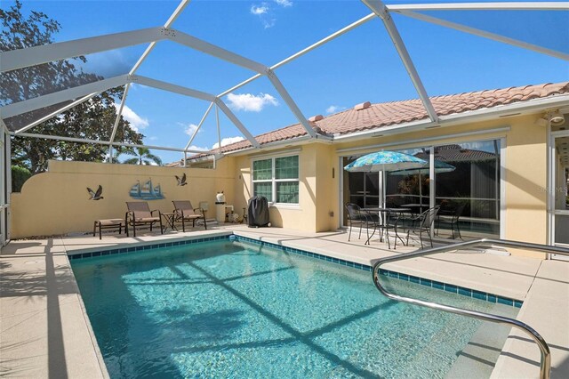 pool featuring glass enclosure and a patio area