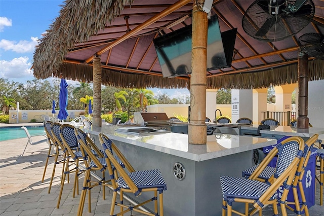 view of patio featuring a community pool, exterior bar, a grill, area for grilling, and a gazebo