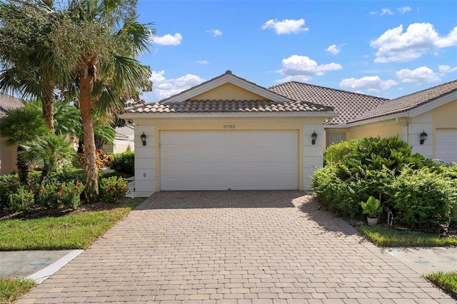 view of front of house featuring decorative driveway, a tiled roof, and stucco siding