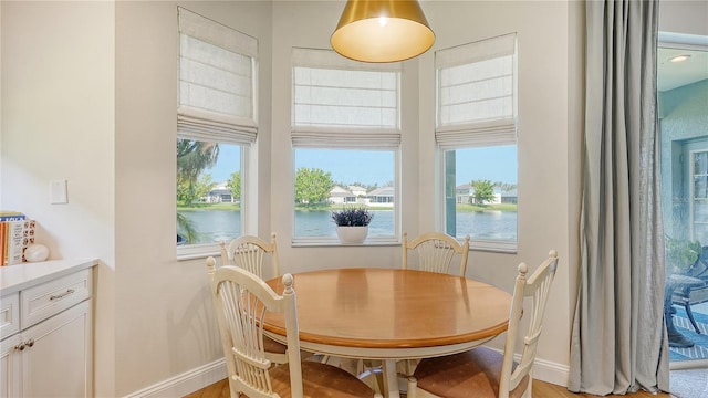 dining space with plenty of natural light, a water view, and light wood-type flooring