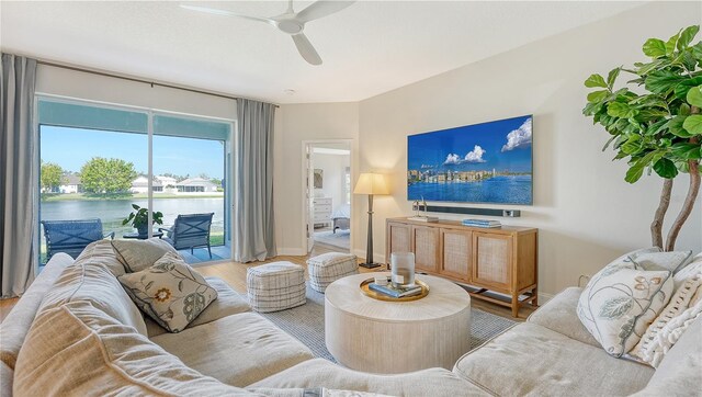 living room with light hardwood / wood-style flooring, a water view, and ceiling fan