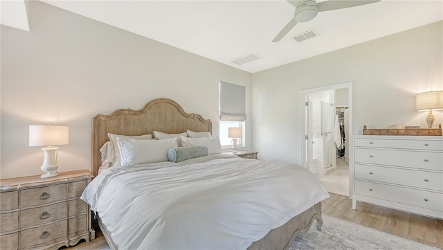 bedroom featuring light wood-type flooring, a spacious closet, a closet, ceiling fan, and connected bathroom