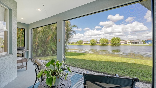 sunroom featuring a water view