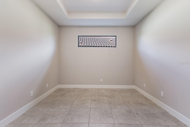 spare room featuring a raised ceiling and light tile patterned floors