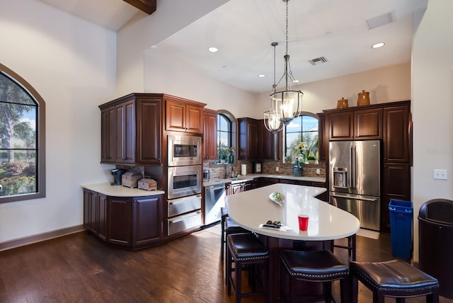 kitchen featuring an inviting chandelier, dark hardwood / wood-style floors, decorative light fixtures, a kitchen island, and stainless steel appliances