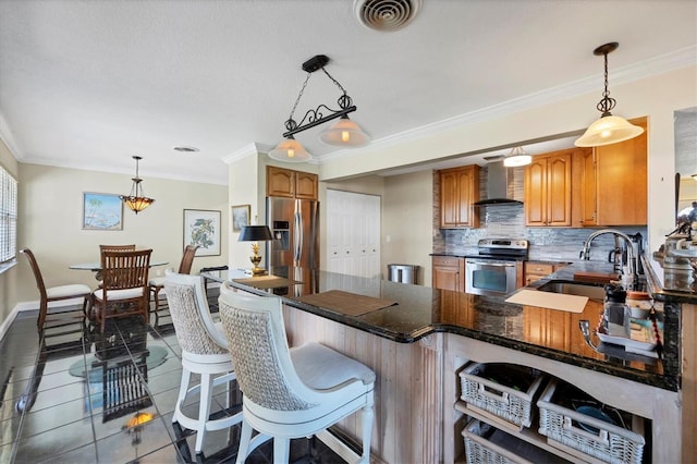 kitchen with wall chimney range hood, appliances with stainless steel finishes, sink, pendant lighting, and tile patterned flooring