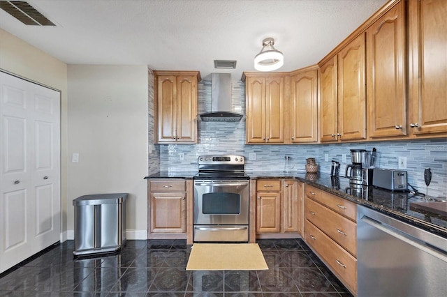 kitchen with stainless steel appliances, wall chimney exhaust hood, dark stone counters, and tasteful backsplash