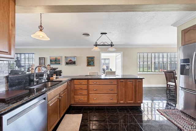 kitchen featuring kitchen peninsula, stainless steel appliances, sink, and pendant lighting