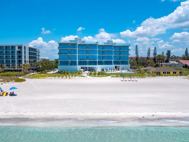 view of building exterior with a water view and a beach view