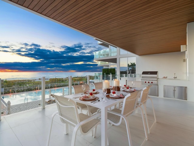 patio terrace at dusk featuring a community pool, grilling area, area for grilling, and sink